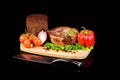 Meat medallion and vegetables on a bread board Royalty Free Stock Photo