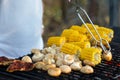 Meat, mushrooms, corn, grilled corn. Outdoor barbecue, hand hold Royalty Free Stock Photo