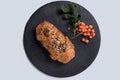 Meat pie with seeds and sprig of rowan on round black rock stand on white background. View from above. Baking to order