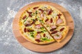 Meat Pizza on wooden board served with green basil pesto sauce. Italian pizza with smoked sausages, ham, champignon mushrooms Royalty Free Stock Photo