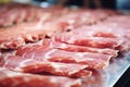 Meat processing plant. Slices of fresh bacon and mint slices on a conveyor belt in the workshop. Arrival of jamon or cold cuts.