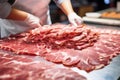 Meat processing plant. A worker sorts cold cuts on a conveyor belt. Arrival of jamon or cold cuts. Production of pork or beef in a Royalty Free Stock Photo