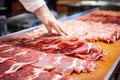 Meat processing plant. A worker sorts cold cuts on a conveyor belt. Arrival of jamon or cold cuts. Production of pork or beef in a