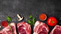 Meat raw steaks lie on black background with vegetables, tomatoes, marasmade, mushrooms. background image. top view Royalty Free Stock Photo