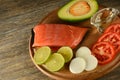 Meat red salmon fish, tomatoes, spices, onion, lemon and olive oil on kitchen table background. Copy space