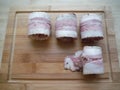 meat rolls in bacon on a wooden table, the cooking process Royalty Free Stock Photo