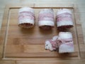 meat rolls in bacon on a wooden table, the cooking process Royalty Free Stock Photo