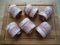 meat rolls in bacon on a wooden table, the cooking process Royalty Free Stock Photo