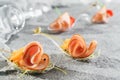 Meat rolls with ham, cheese and onion seedlings in glass spoon on grey banquet table