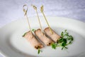 Meat rolls on skewers on white plate. Various snacks