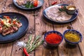 Meat and sausage cuts, garlic, chili peppers, tomatoes and other spices on a wooden brown background