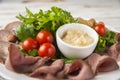 Meat and sausage sliced on a plate with nuts, garlic sauce. Pastrami, baked ham, chorizo, bacon, olives, cherry tomatoes on a plat Royalty Free Stock Photo