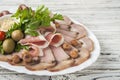 Meat and sausage sliced on a plate with nuts, garlic sauce. Pastrami, baked ham, chorizo, bacon, olives, cherry tomatoes on a plat Royalty Free Stock Photo