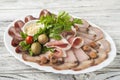 Meat and sausage sliced on a plate with nuts, garlic sauce. Pastrami, baked ham, chorizo, bacon, olives, cherry tomatoes on a plat Royalty Free Stock Photo