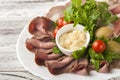 Meat and sausage sliced on a plate with nuts, garlic sauce. Pastrami, baked ham, chorizo, bacon, olives, cherry tomatoes on a plat Royalty Free Stock Photo