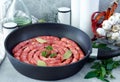 Meat sausages in frying pan, with bay leaves and fresh herbs in the kitchen Royalty Free Stock Photo