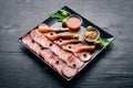 Meat slices on a plate with ketchup and mustard. Sausage and bacon. On a wooden background. Royalty Free Stock Photo