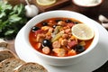 Meat solyanka soup with sausages, olives and vegetables on table, closeup