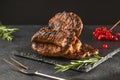 Meat steak with rosemary grilled on a black stone board. Side view