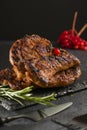 Meat steak with rosemary grilled on a black stone board. Side view. Vertical position