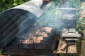 Meat steaks are grilled on an outdoor street grill. Man cooks barbecue and adds spices. Summer picnic in nature. Royalty Free Stock Photo