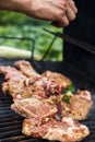 Meat steaks are grilled on an outdoor street grill. Man cooks barbecue and adds spices. Summer picnic in nature. Royalty Free Stock Photo