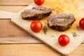 Meat steaks on a wooden tray on a wooden background. Top view Royalty Free Stock Photo