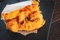 meat strips in a paper bag on a black tray. strips of meat fried in breading. Royalty Free Stock Photo