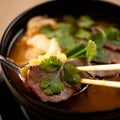 Meat thai soup with onion and parsley. Close up shot. Eating lunch with chopsticks. Spicy oriental dish, Pan-Asian