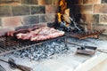 The meat of a traditional Argentine barbecue being roasted on a grill located in the patio of a house.