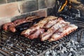 The meat of a traditional Argentine barbecue being roasted on a grill located in the patio of a house.