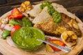 Meat with vegetables, grilled and served Italian Salsa Verde sauce. Wooden rustic table. Close-up