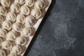 Meat or vegeterian dumplings, pelmeni on a wooden board on a dark grey table. Russian national food. Close up top view. Royalty Free Stock Photo