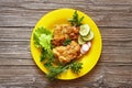 Meat in the yellow plate and green salad on a wooden background Royalty Free Stock Photo