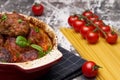 Meatballs with cherry tomato sauce and decorated with basil leaf, served in white and red pan on grey background. next to the pan Royalty Free Stock Photo