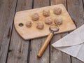 Meatballs ready for frying laid out on a wooden kitchen board