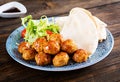Meatballs in sweet and sour glaze on a plate with pita bread and vegetables