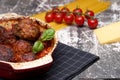 Meatballs with tomato sauce and decorated with basil leaf, served in white and red pan on grey background. next to the pan near Royalty Free Stock Photo