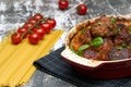 Meatballs with tomato sauce and decorated with basil leaf, served in white and red pan on grey background. next to the pan near Royalty Free Stock Photo