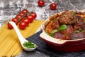 Meatballs with tomato sauce and decorated with basil leaf, served in white and red pan on grey background. next to the pan near Royalty Free Stock Photo