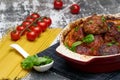 Meatballs with tomato sauce and decorated with basil leaf, served in white and red pan on grey background. next to the pan near Royalty Free Stock Photo