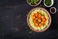 Meatballs in tomato sauce with mashed potatoes in bowl.