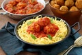 Meatballs in tomato sauce in metal pan on table with italian pasta Royalty Free Stock Photo