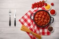 Meatballs in tomato sauce with spices in a frying pan on a white wooden board