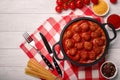 Meatballs in tomato sauce with spices in a frying pan on a white wooden board