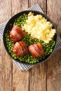 Meatballs wrapped in bacon faggot with green peas and mashed potatoes close-up in a plate. vertical top view Royalty Free Stock Photo