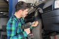 Mecanic checking car suspension system, at repair service station.