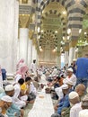 Male worshipers sit in a row waiting to break their fast inside the Prophet\'s Mosque