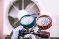 Mechanic air conditioner technician using manifold gauge checking refrigerant for filling home air conditioning and air duct Royalty Free Stock Photo