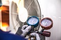 Mechanic air conditioner technician using manifold gauge checking refrigerant for filling home air conditioning and air duct Royalty Free Stock Photo